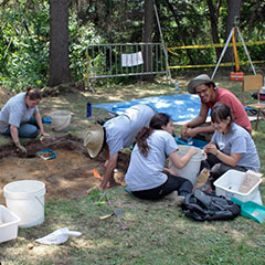Colour photograph of trainee archaeologists digging the ground.