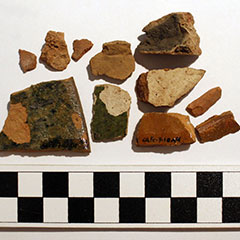 Colour photograph of several orange terracotta shards. They all have different shapes and sizes.