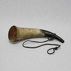 Photographie couleur d'une corne noire et blanche. Une corde y est attachée.