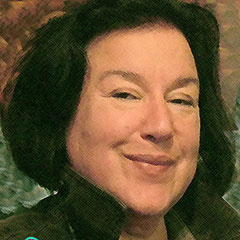Photographie couleur d'une femme souriant au cheveux noirs. Elle porte une chemise verte.