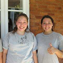 Colour photograph of three young ladies. They are smiling and showing a thumbs up.