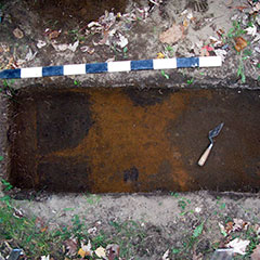 Photographie couleur d'une couche de sol avec une section rougie, et d'une truelle.