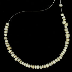 Photographie couleur d'un collier de perles blanches en verre.