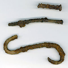 Colour photograph of three iron pieces: two nails and a hook.