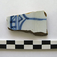 Colour photograph of a white earthenware shard with blue patterns.