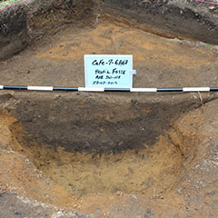 Colour photograph of a pit, (blackened area), in lighter grounds.