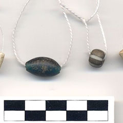 Photographie couleur de différentes perles de couleur, matériaux et tailles variés enfilées sur des fils.